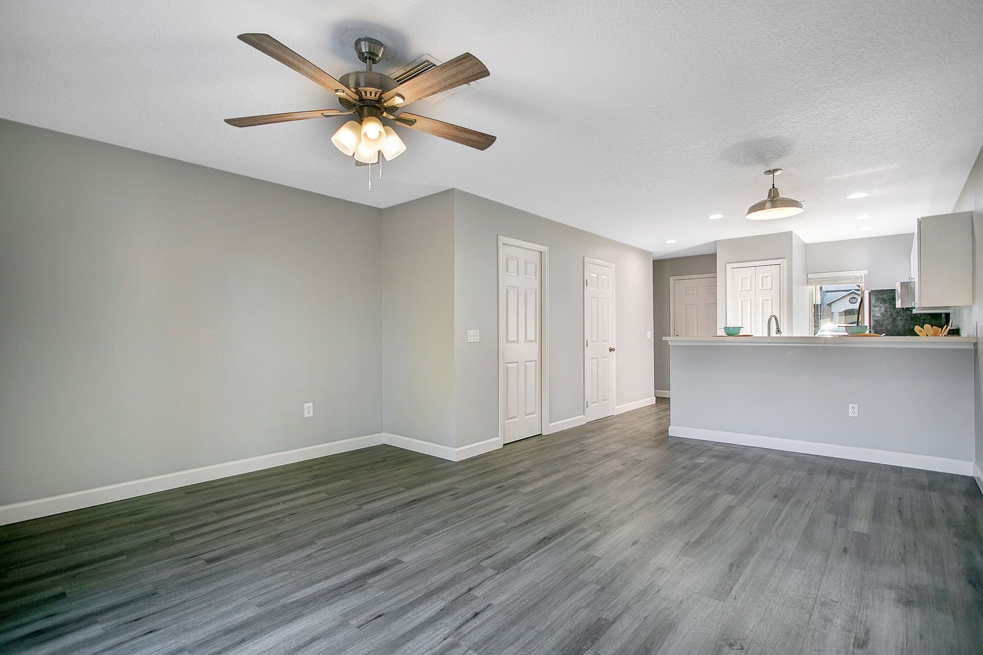 A living room with hardwood floors and a ceiling fan.