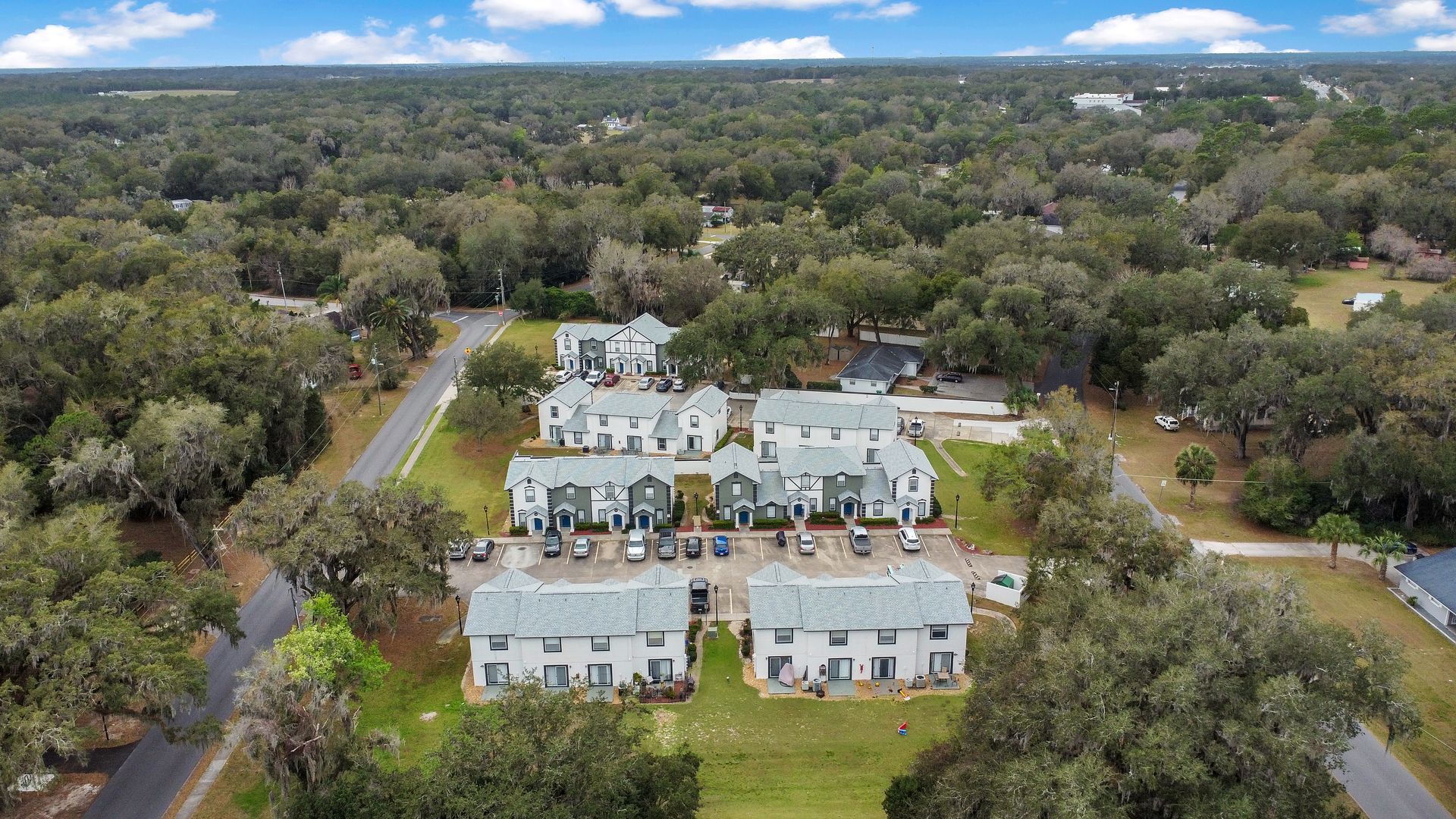 An aerial view of a residential area with lots of trees and apartment homes.
