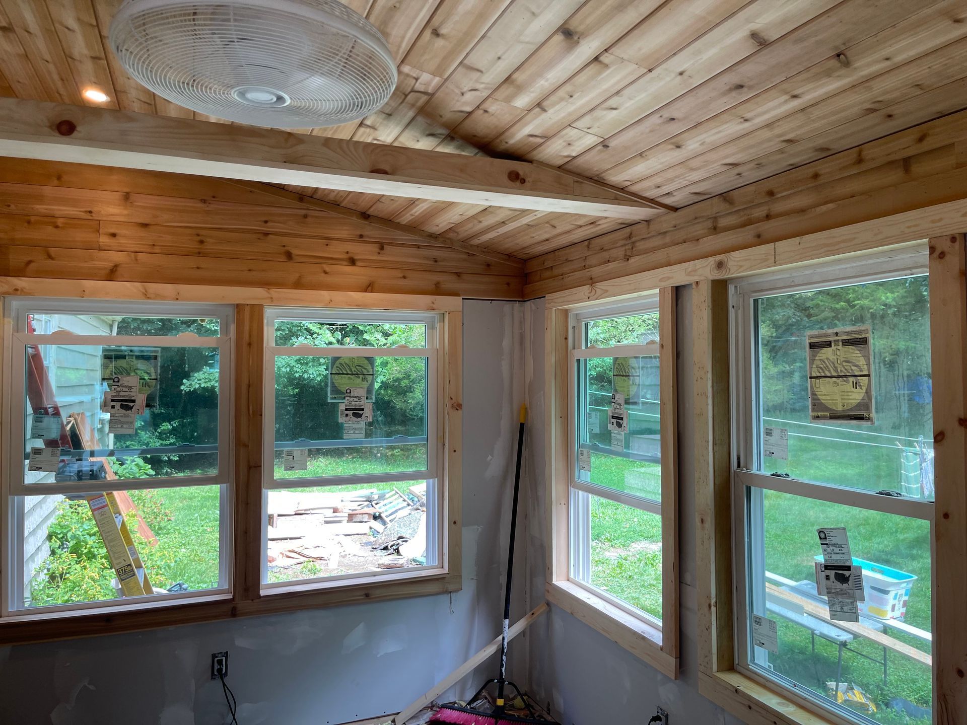 A room with a lot of windows and a fan on the ceiling.