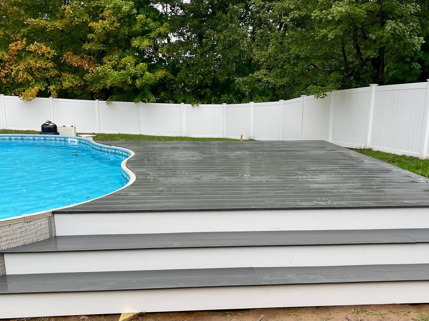 A swimming pool with a wooden deck and stairs next to it.