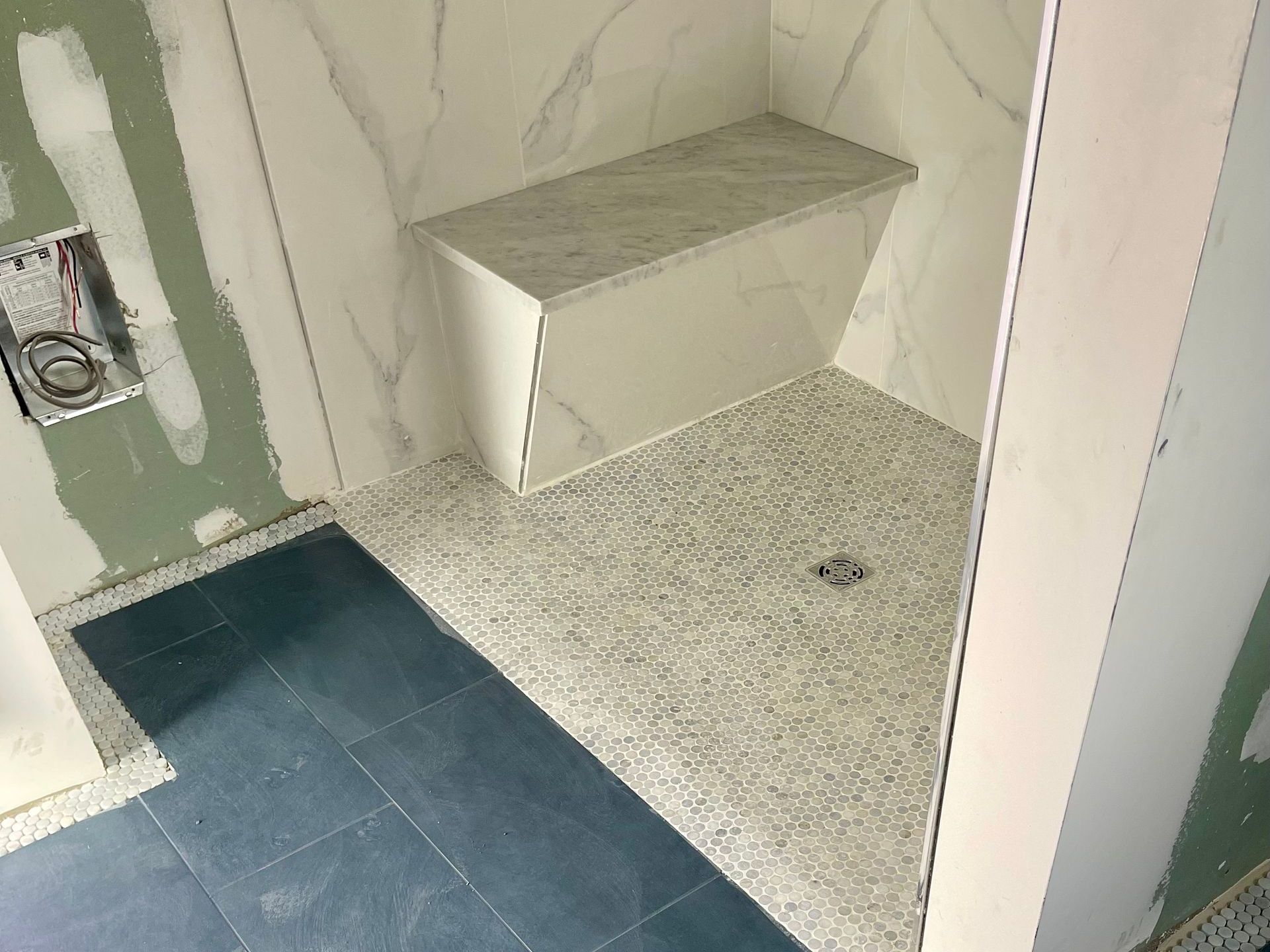 A bathroom with a walk in shower and a bench.