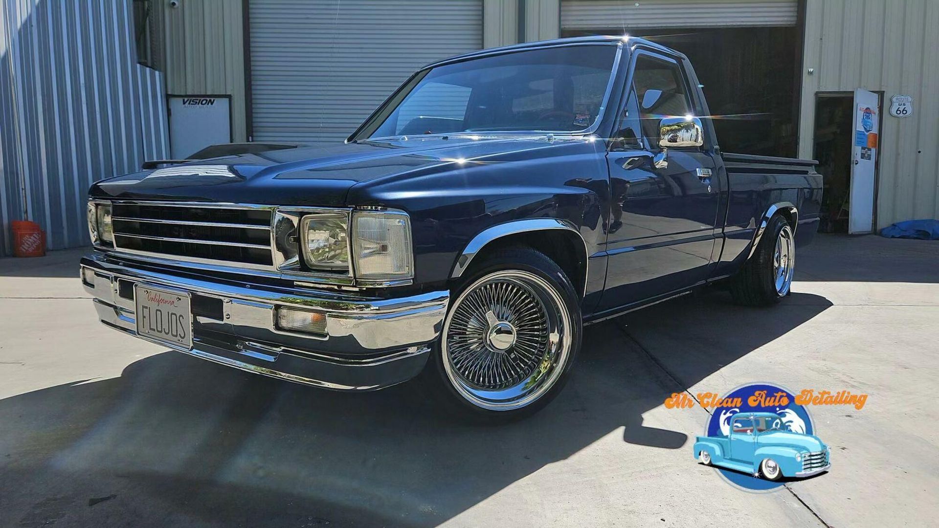 A blue truck is parked in front of a garage.