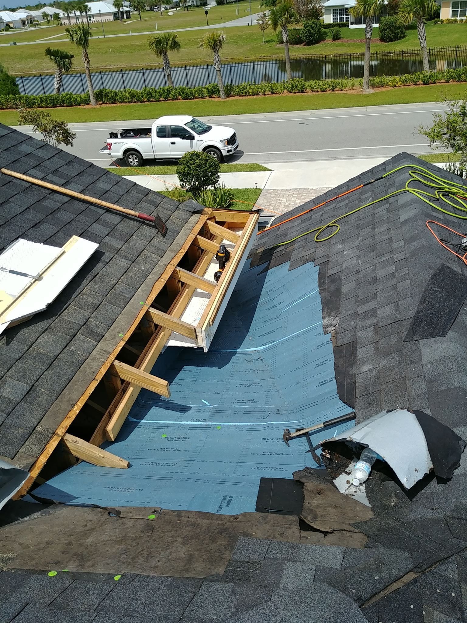 Roof shingle repair in progress with nail gun and hammer.