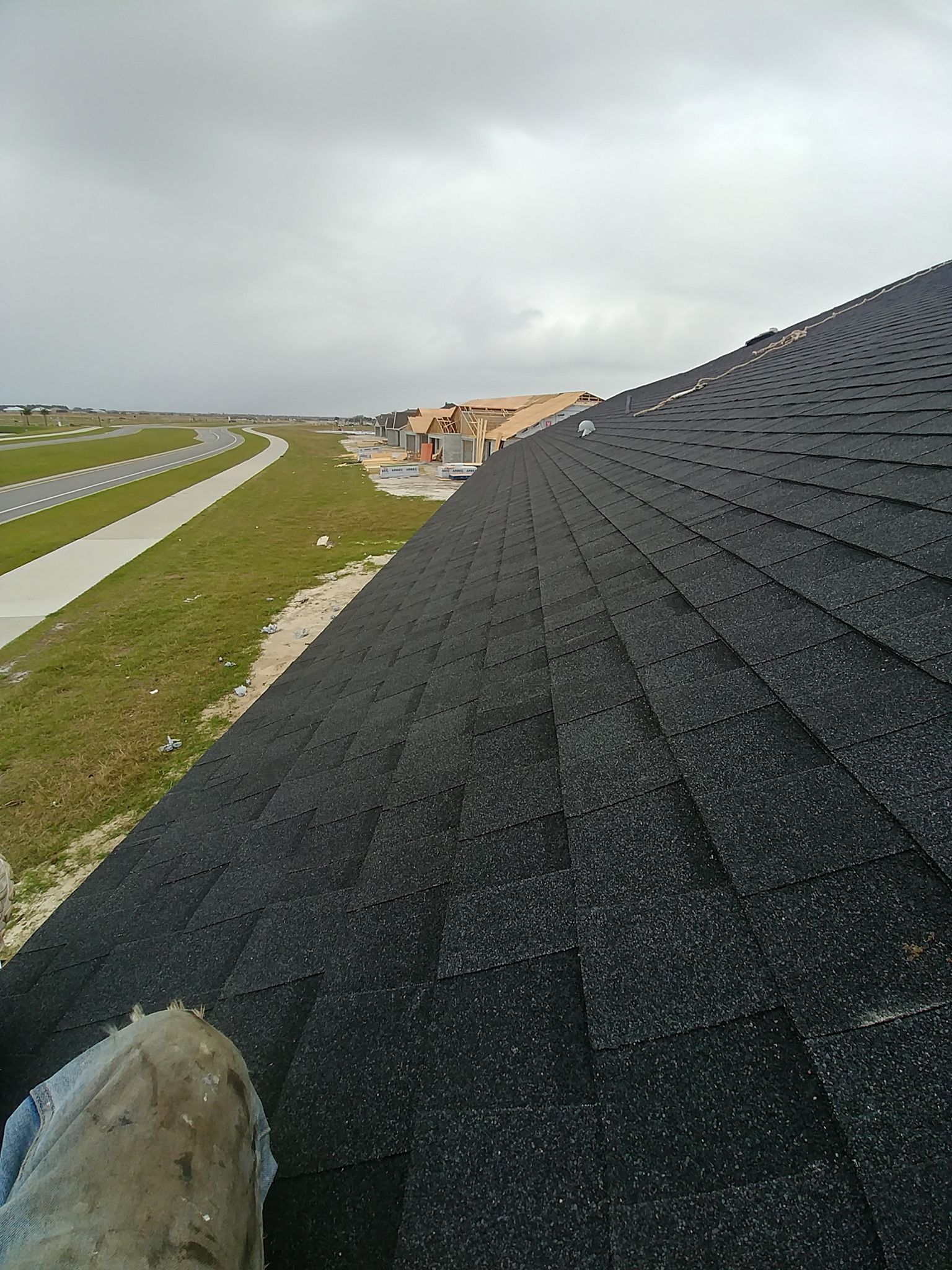 A person is holding a piece of asphalt on top of a roof.