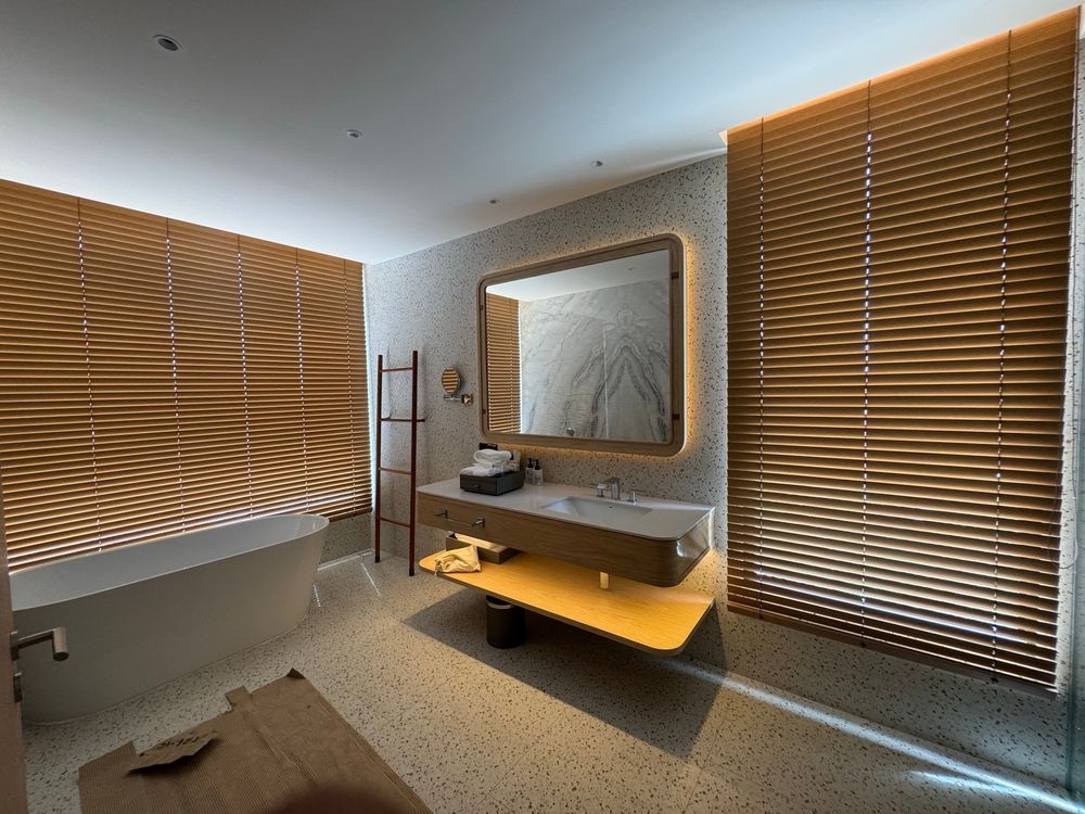 Modern bathroom with wood paneling, bathtub, and large mirror.