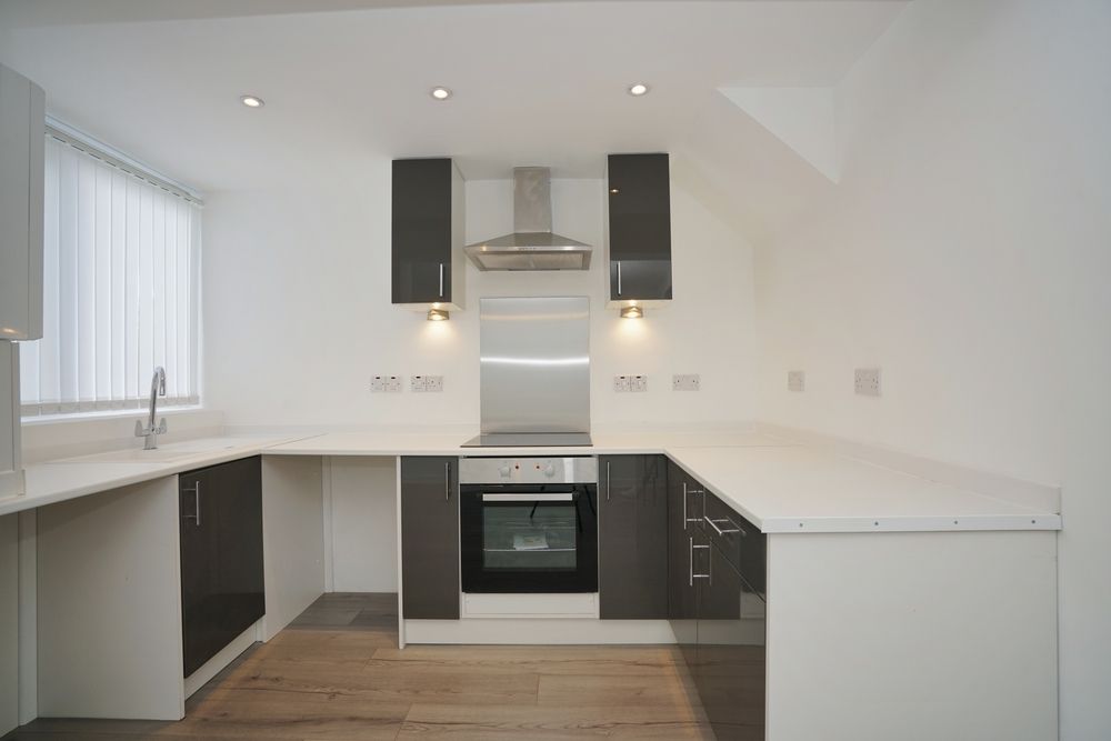 Modern kitchen with gray cabinets, white countertops, and stainless steel appliances.