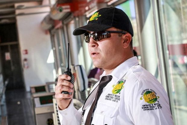 Un hombre que lleva sombrero y gafas de sol está hablando por un walkie talkie.