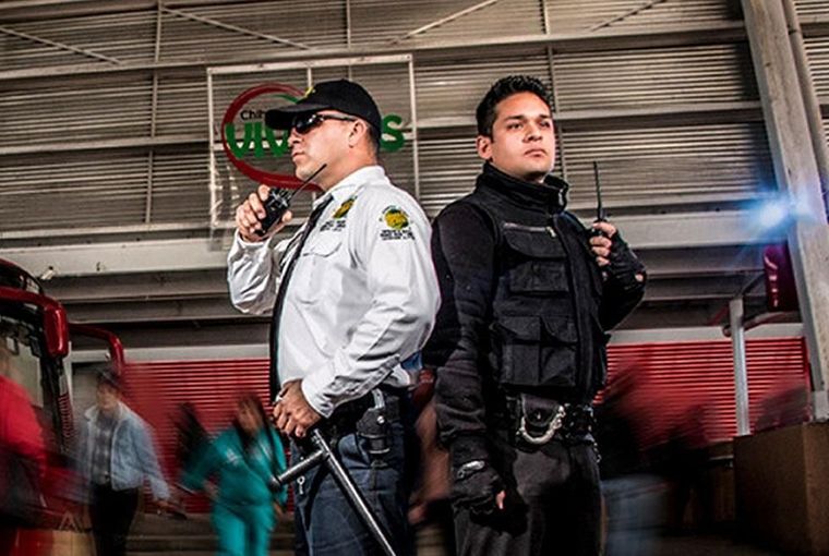 Dos guardias de seguridad están parados uno al lado del otro en un edificio.