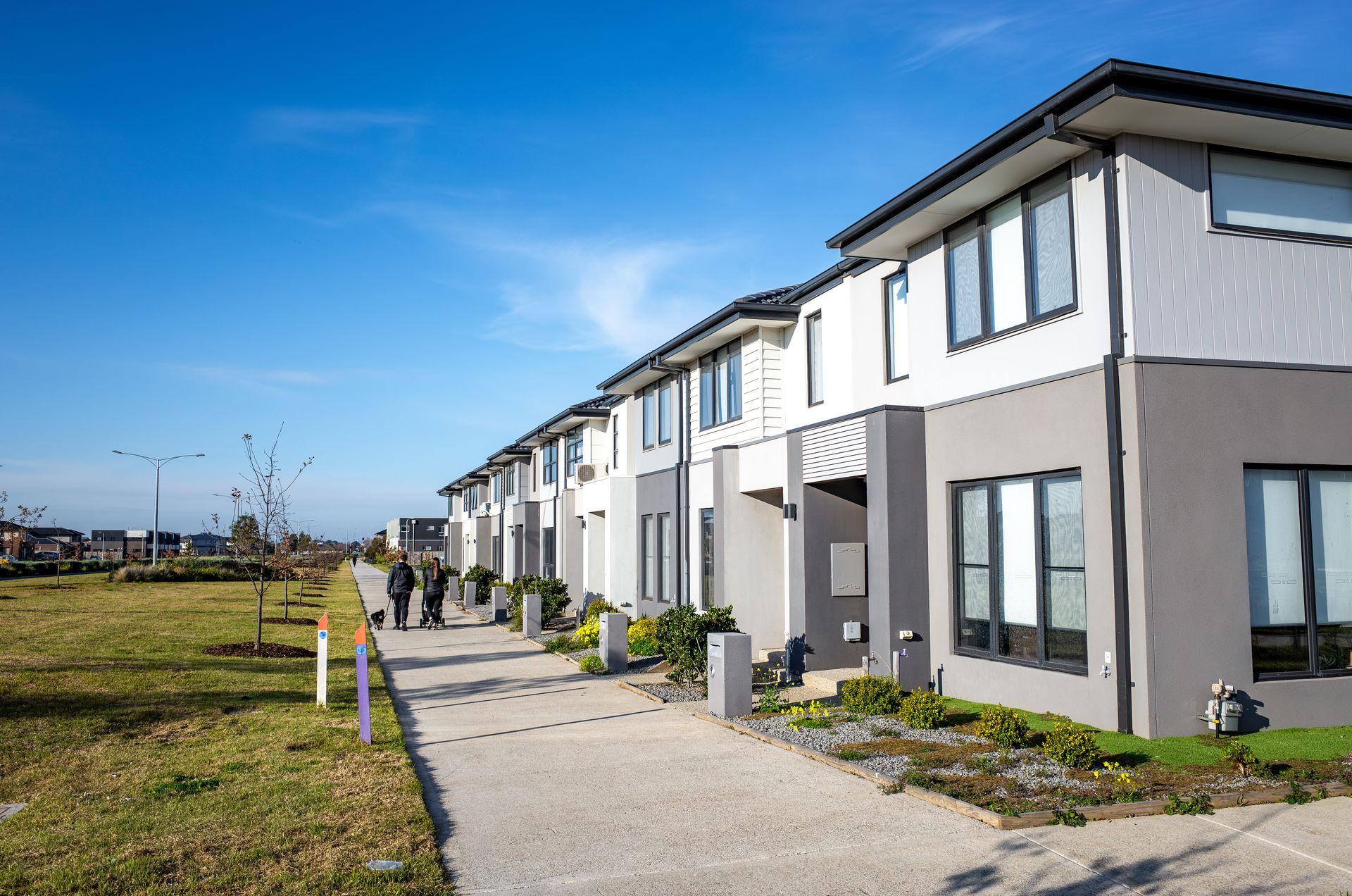 Row of modern two-story townhouses with gray and white exteriors under a clear blue sky.