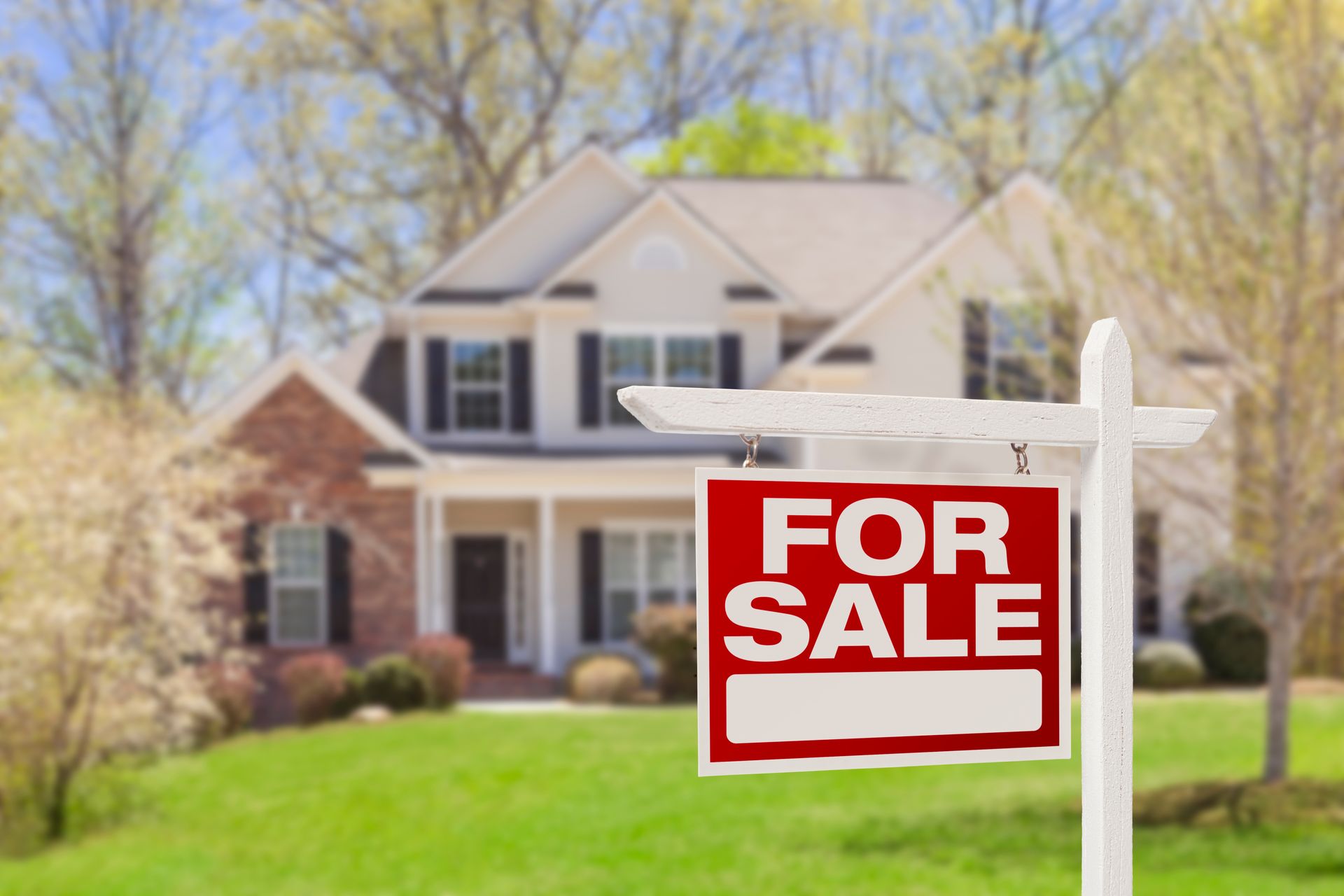 A house with a red For Sale sign in the front yard.