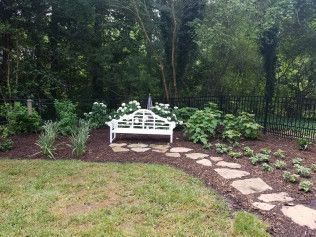White bench on a stone path in a garden