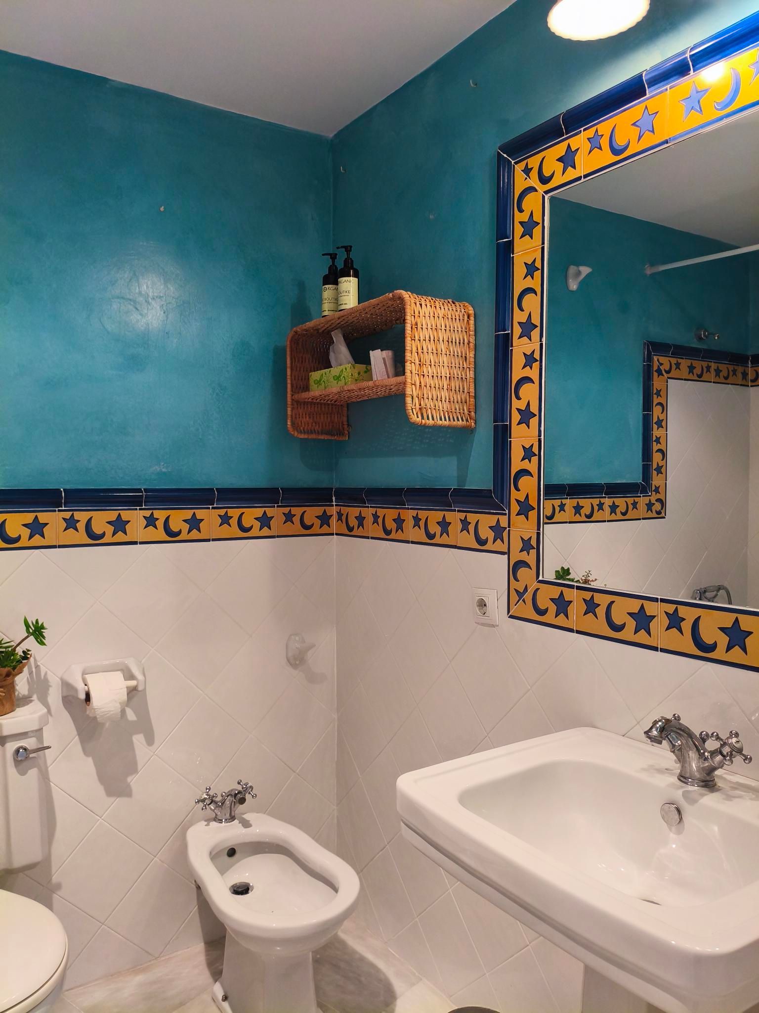 Bathroom with turquoise walls, white fixtures, and a decorative mirror and trim with crescent moon and star patterns.