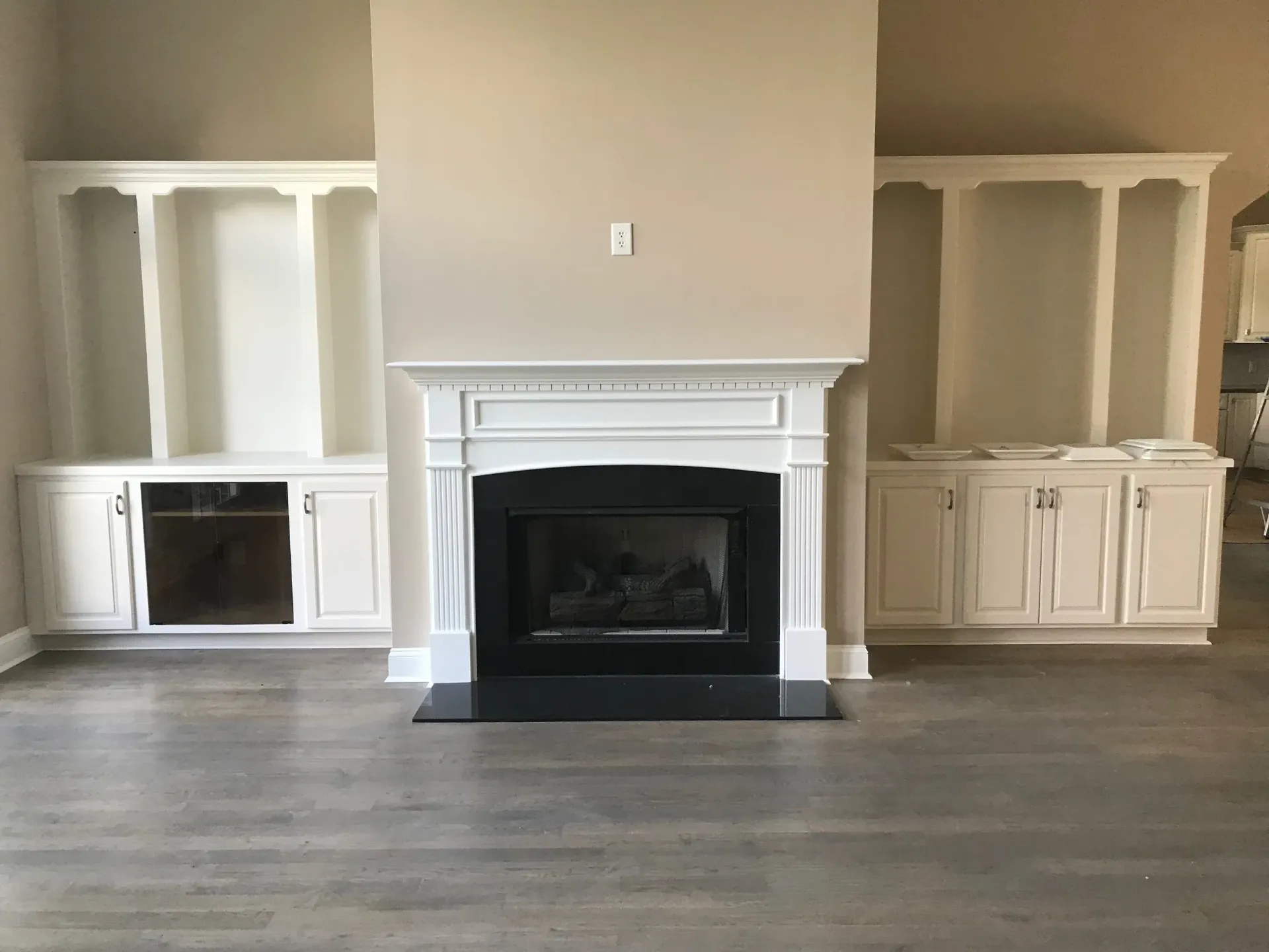 An empty living room with a fireplace and shelves