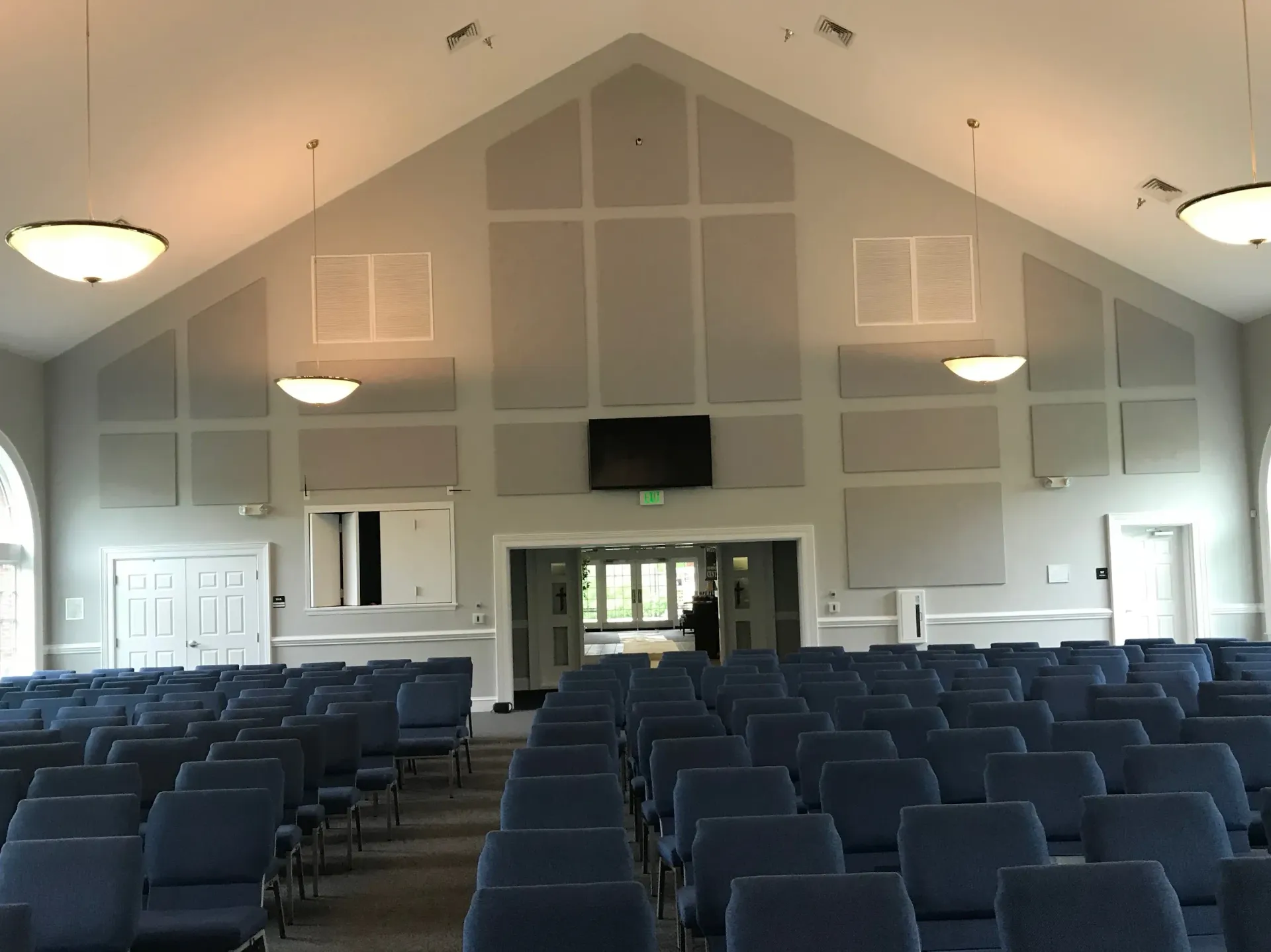 Rows of blue chairs in a church with a vaulted ceiling