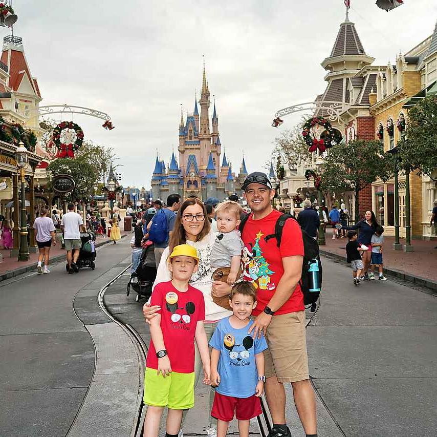 Family posing on Main Street at Disney World in front of Cinderella Castle.