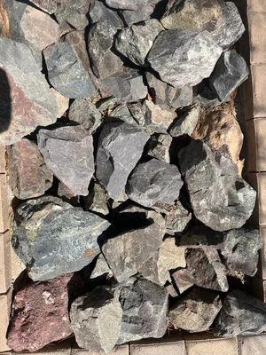Pile of gray and reddish-brown rocks on a light-colored surface.