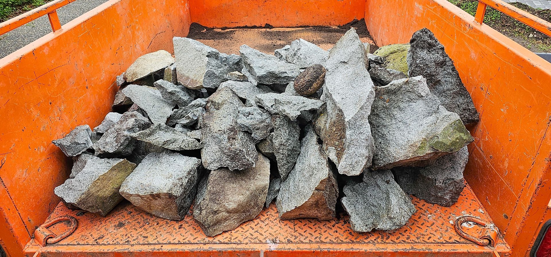 Woman in straw hat smiles, holding wine glass near a lake.