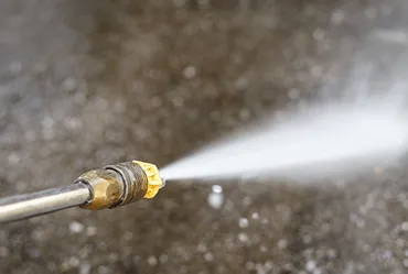 Pressure washer spraying water on concrete.