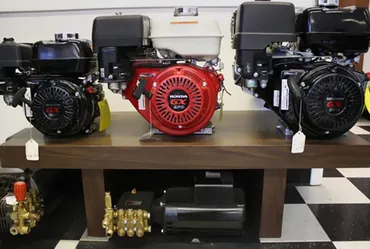 Three small engines on a shelf, one red, two black. Underneath, a pressure washer.