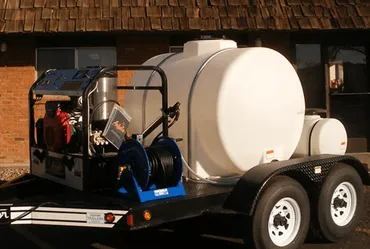 Trailer with water tanks and pressure washer, outdoors.