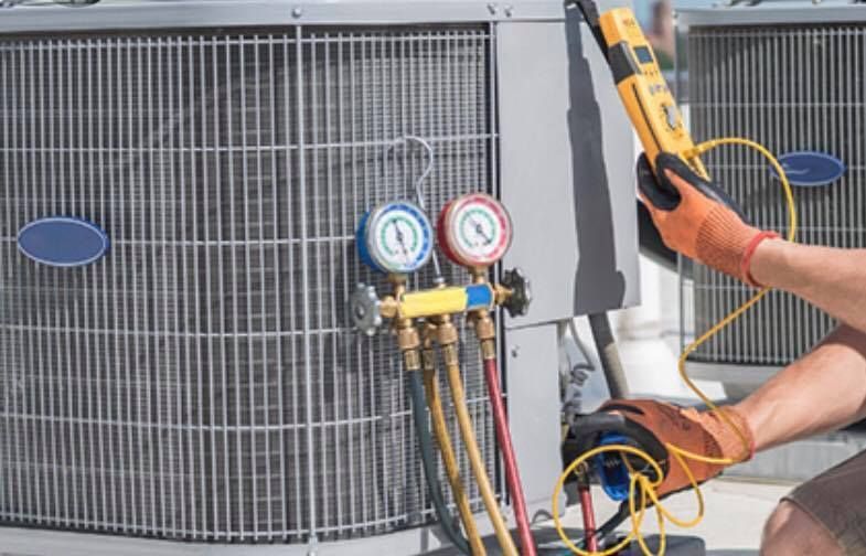 A man is working on an air conditioner with a thermometer.