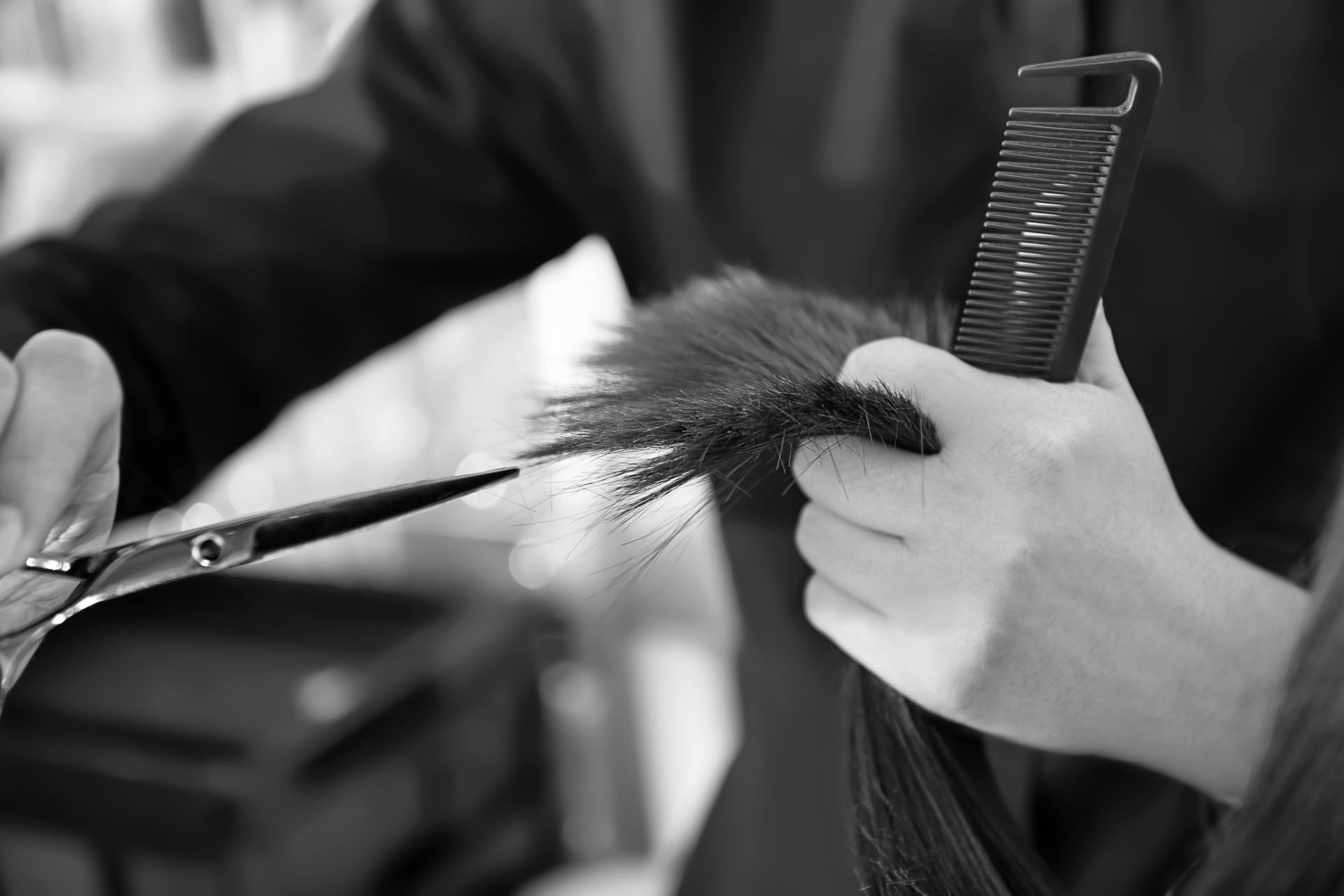 A person is cutting their hair with scissors and a comb.