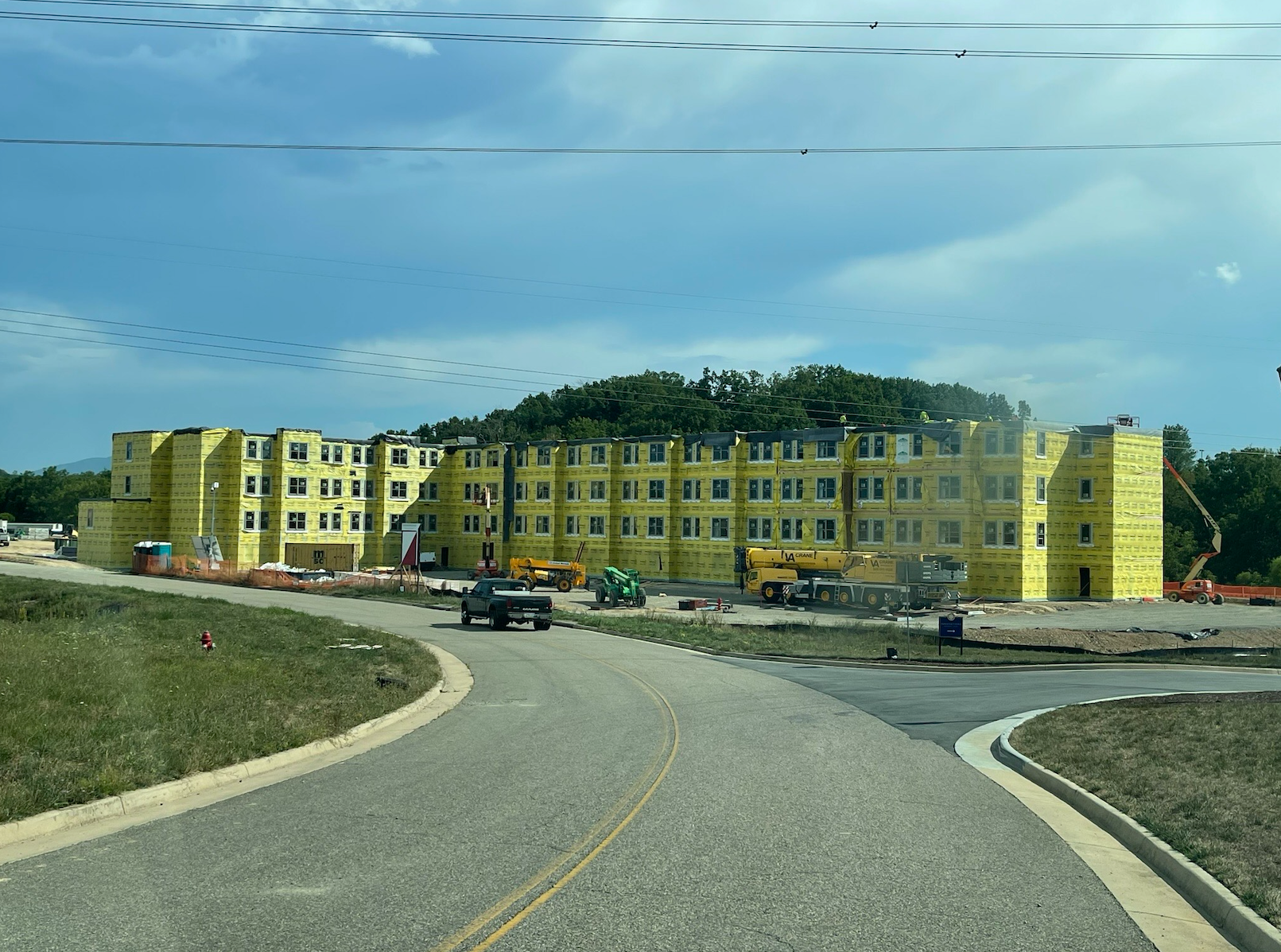 A large yellow building is being built on the side of a road.