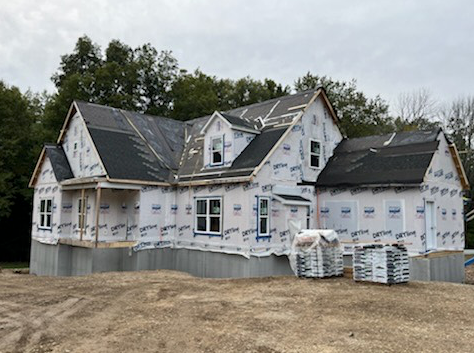 A large house is being built on a dirt field.