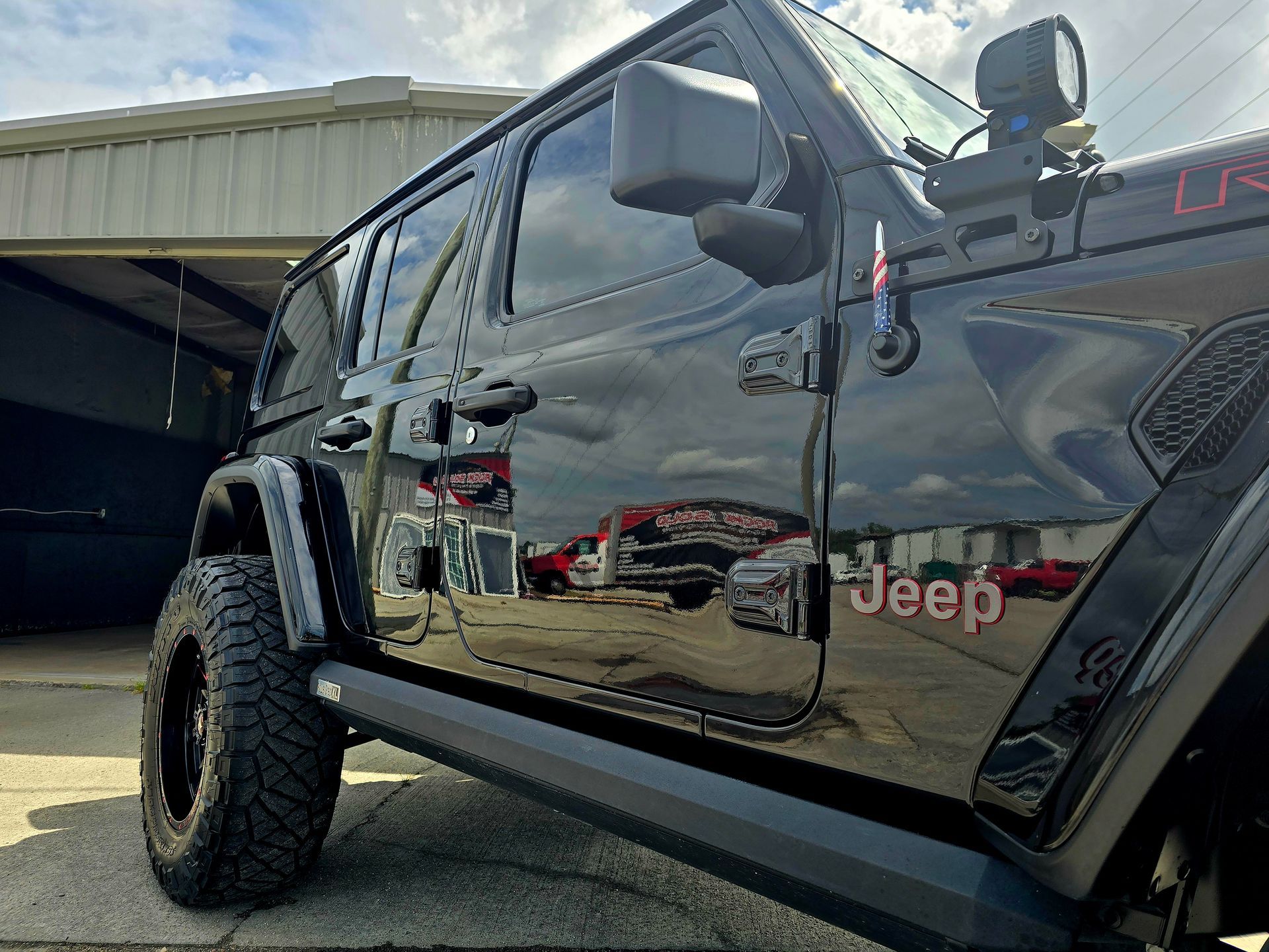 A black jeep is parked in front of a garage.