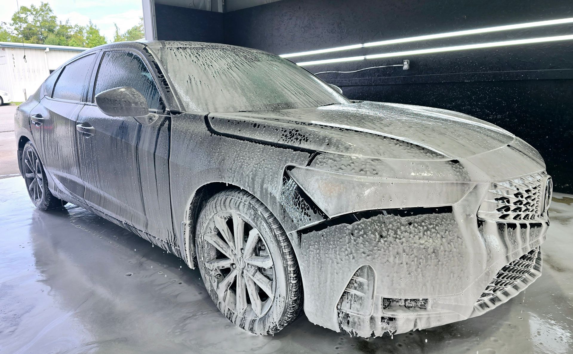 A car is covered in foam in a garage.