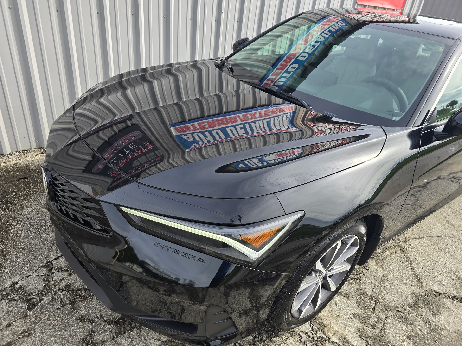 A black car is parked in front of a building.