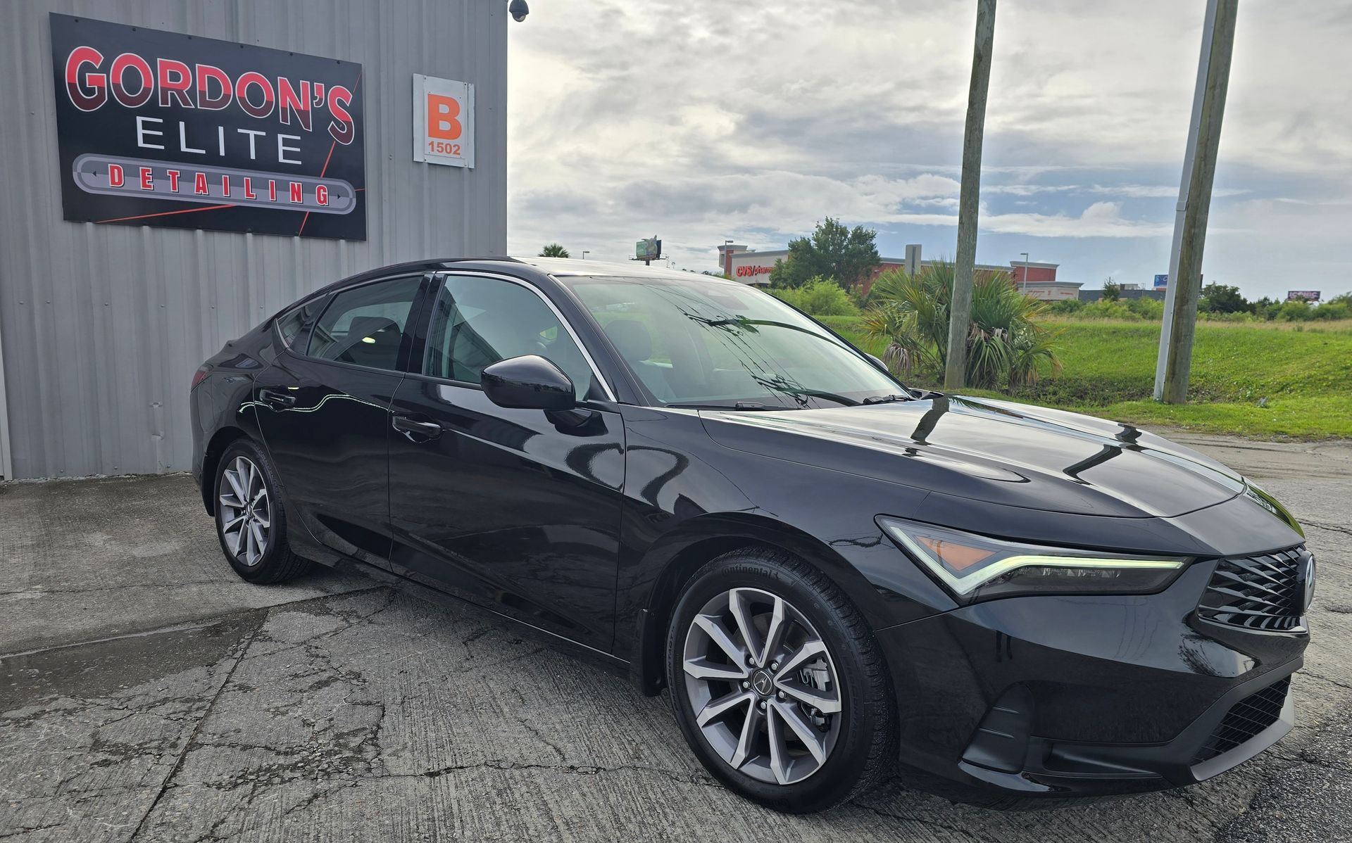 A black car is parked in front of a building.