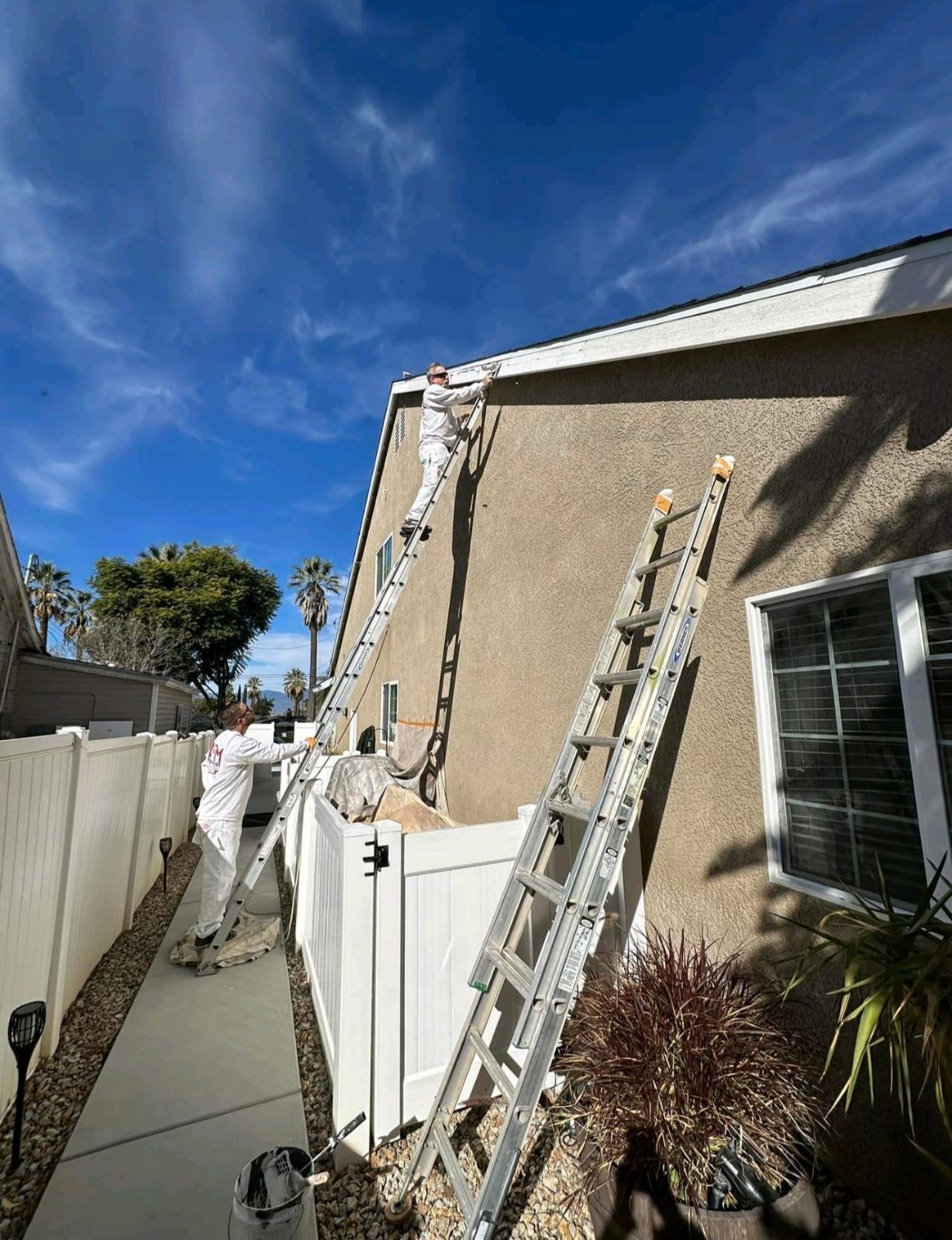 Damien is painting the side of a house with a ladder in Redlands CA .