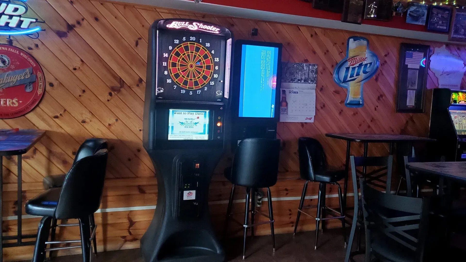 A dart board and a miller lite machine in a bar