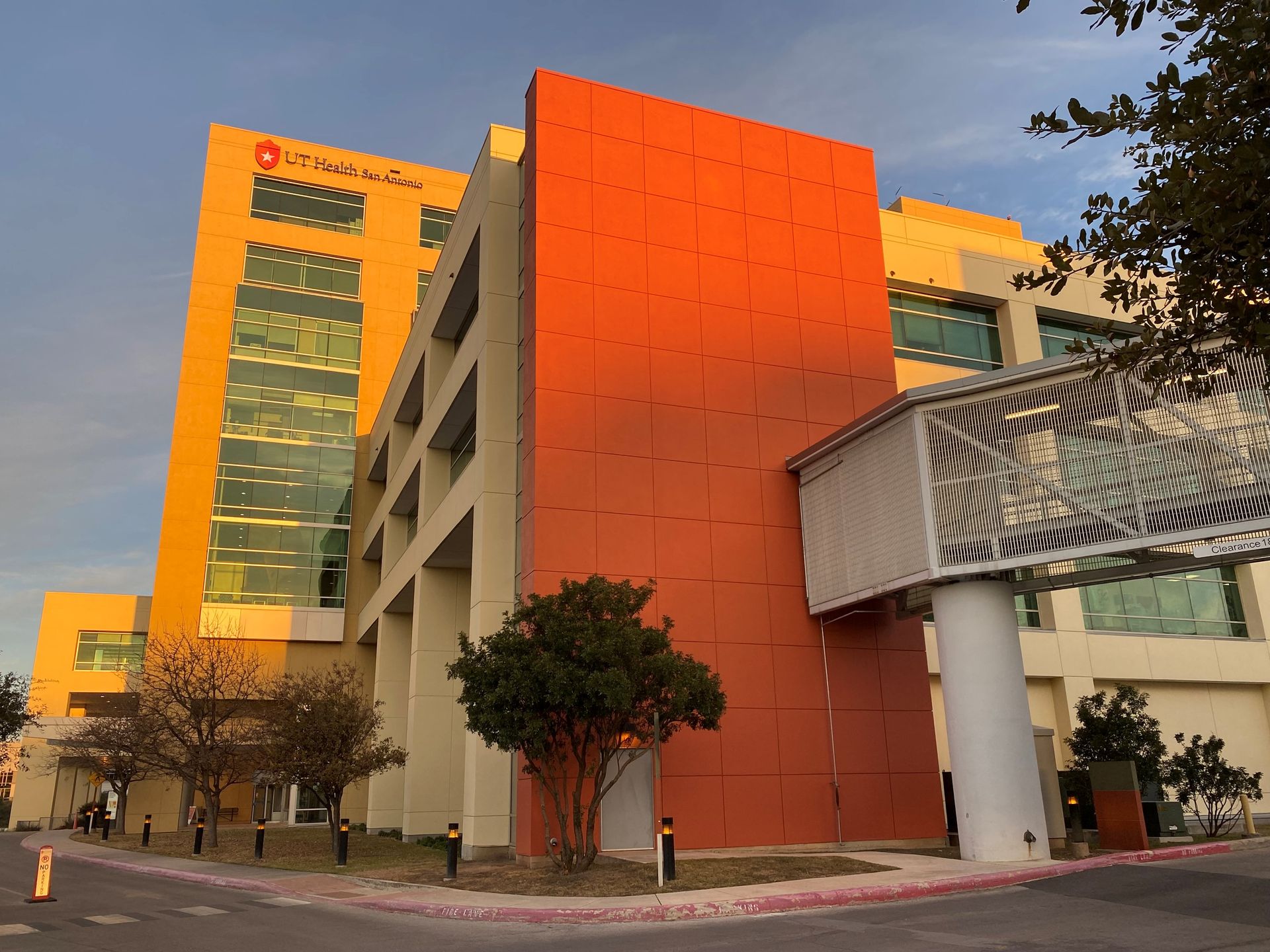 Hospital building with orange and yellow exterior. Sky bridge connects to a white structure.