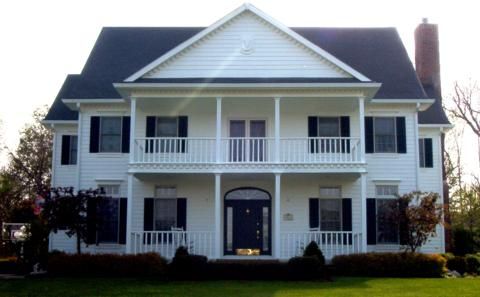 A large white house with black shutters and a blue door