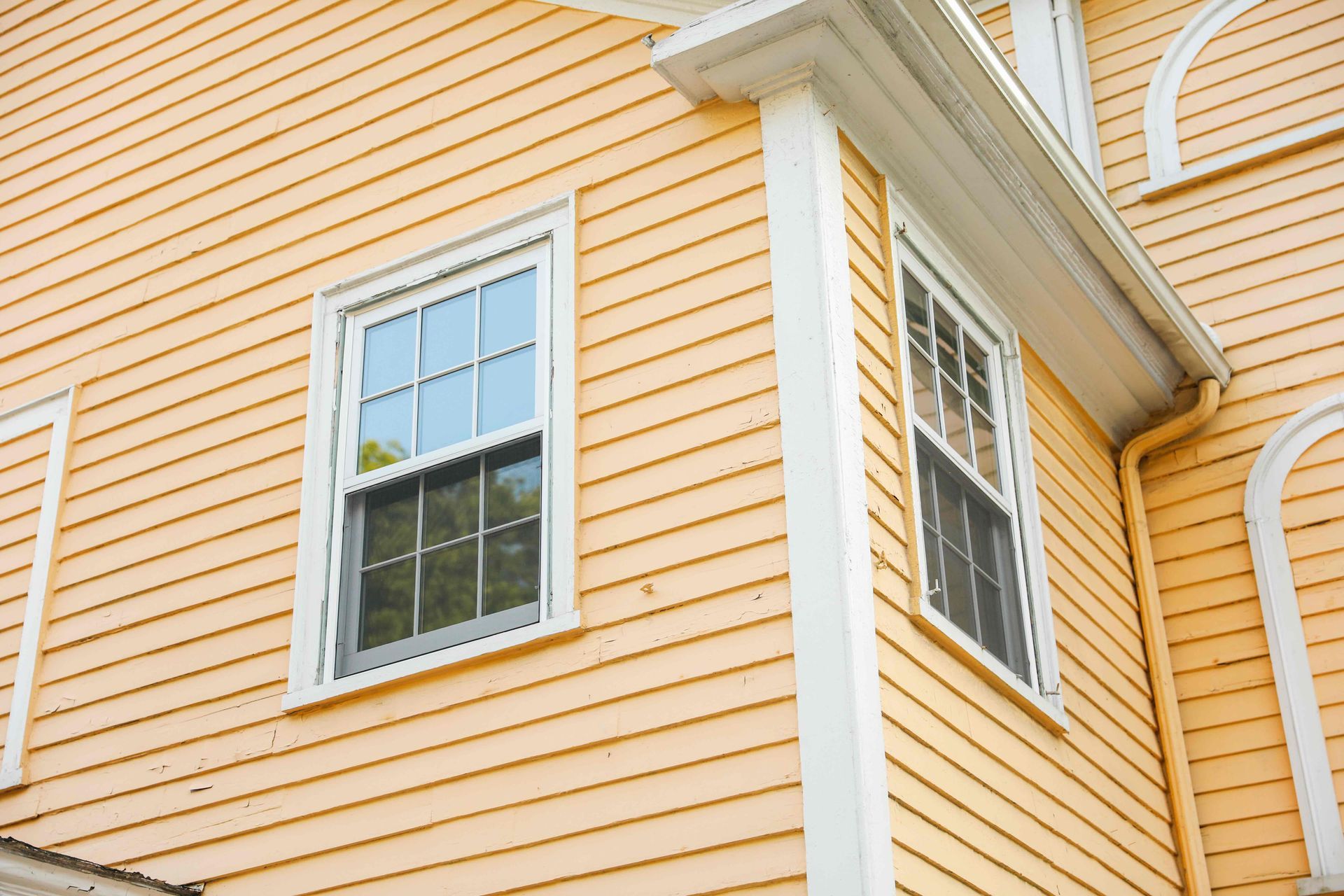 a close up of a yellow house with white trim and windows .