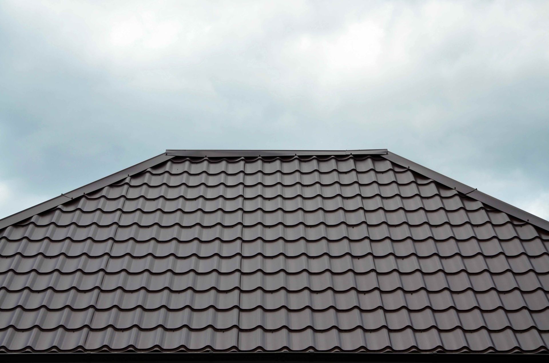 a close up of a brown roof with a cloudy sky in the background .