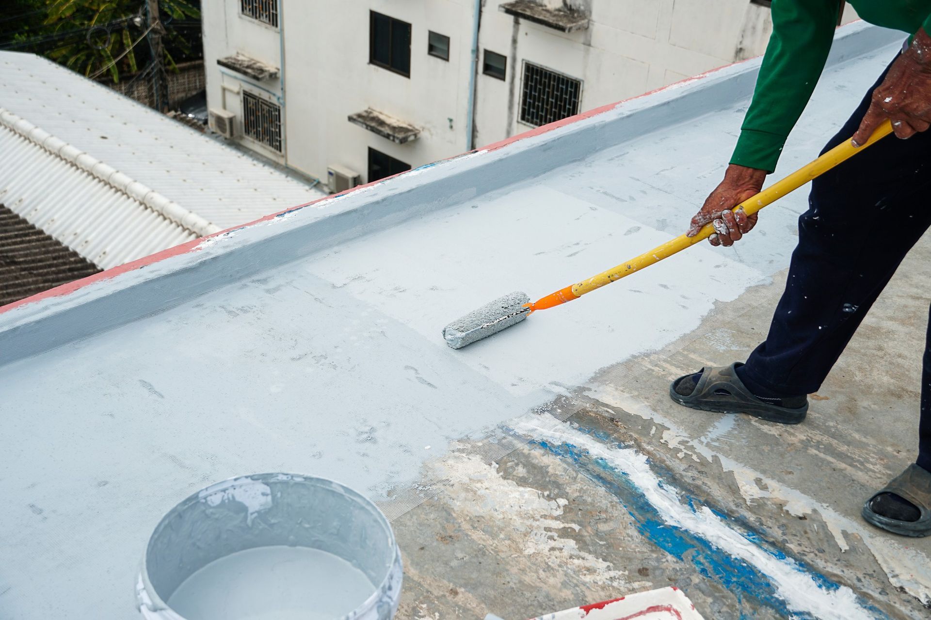 A man is painting a roof with a roller.