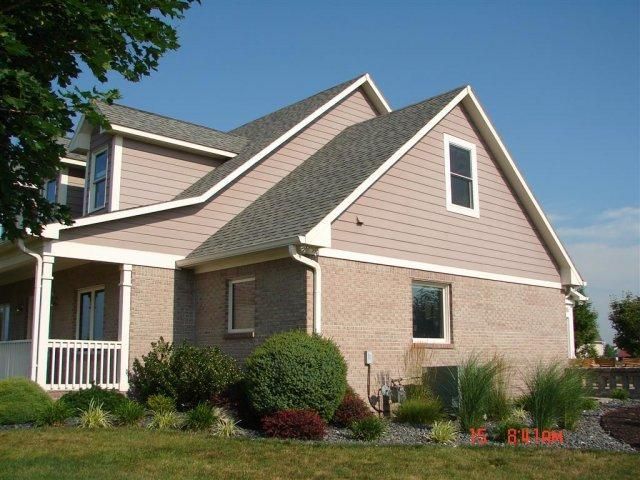 A brick house with a porch and a gray roof