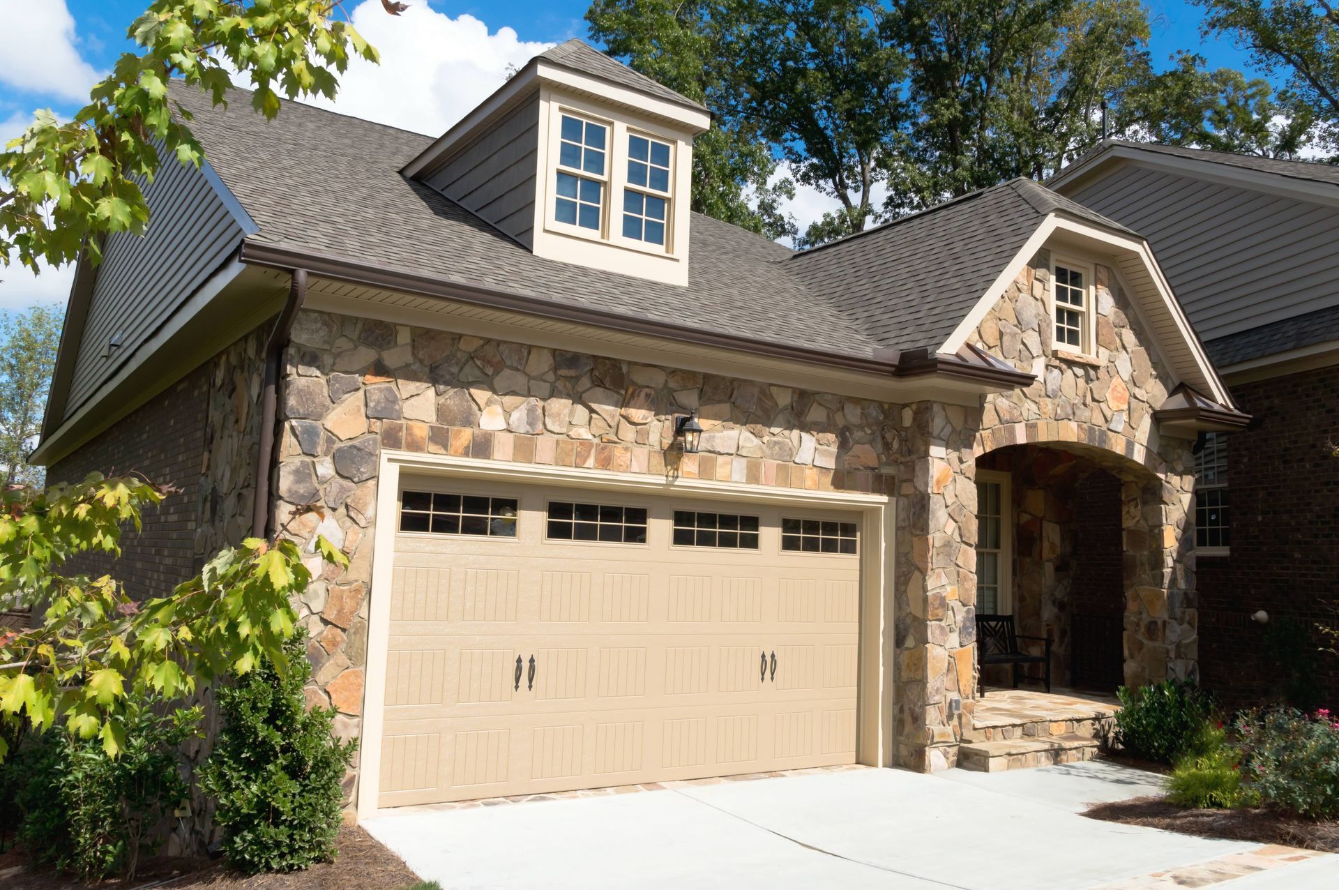 a house with a large garage door and a stone facade .