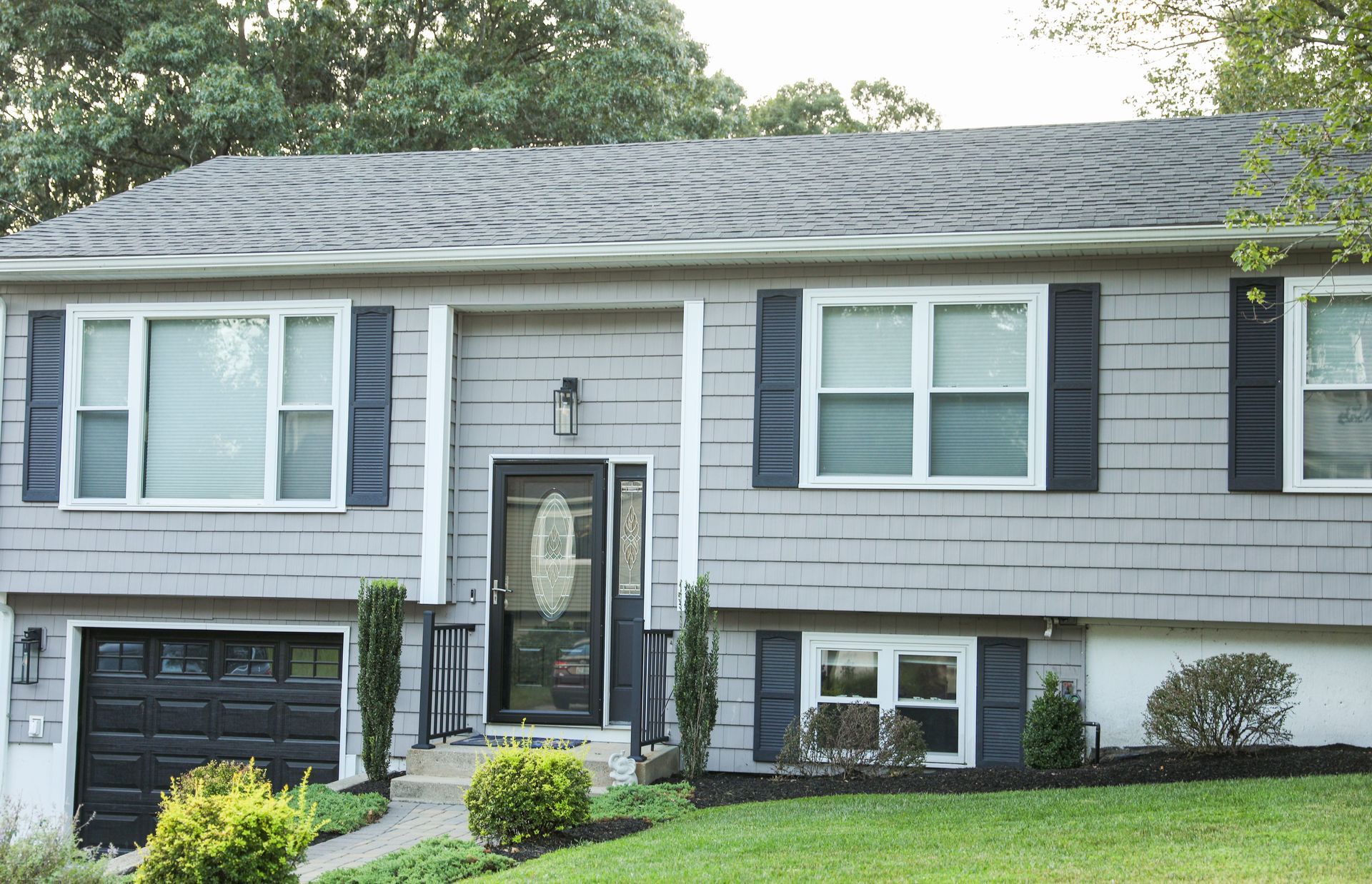 a gray house with black shutters and a black garage door