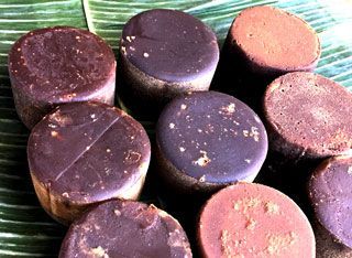 A bunch of chocolate candies are sitting on top of a green leaf.