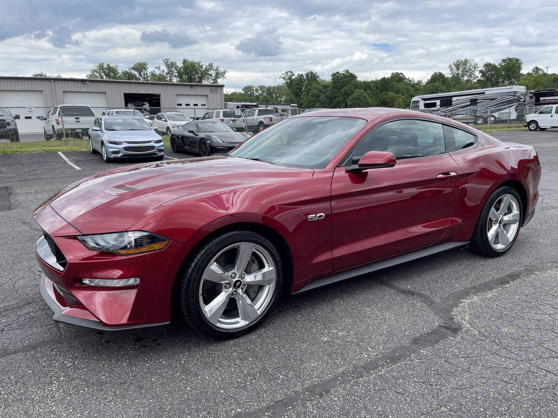 A red ford mustang is parked in a parking lot.