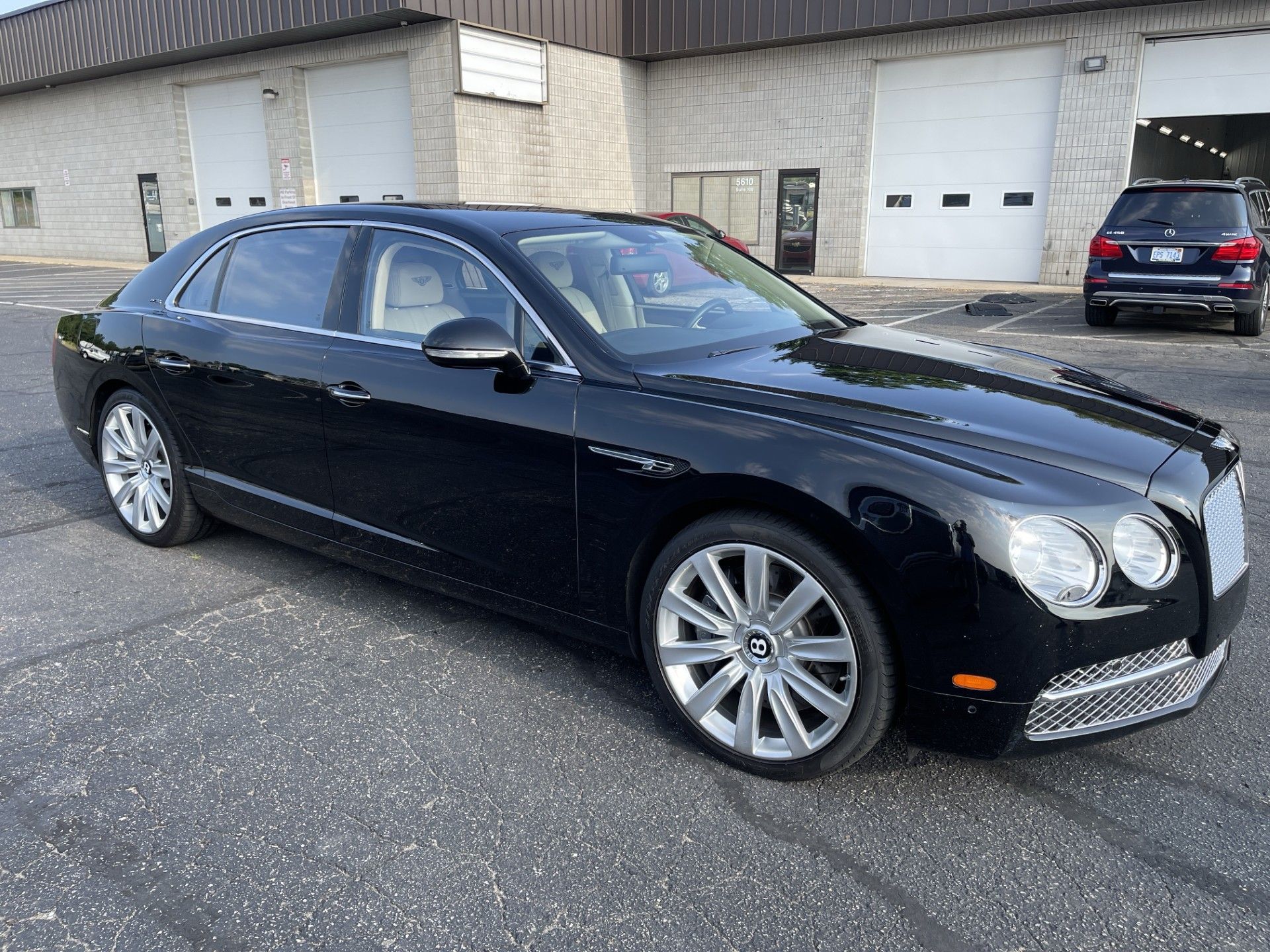 A black bentley continental flying spur is parked in front of a building.