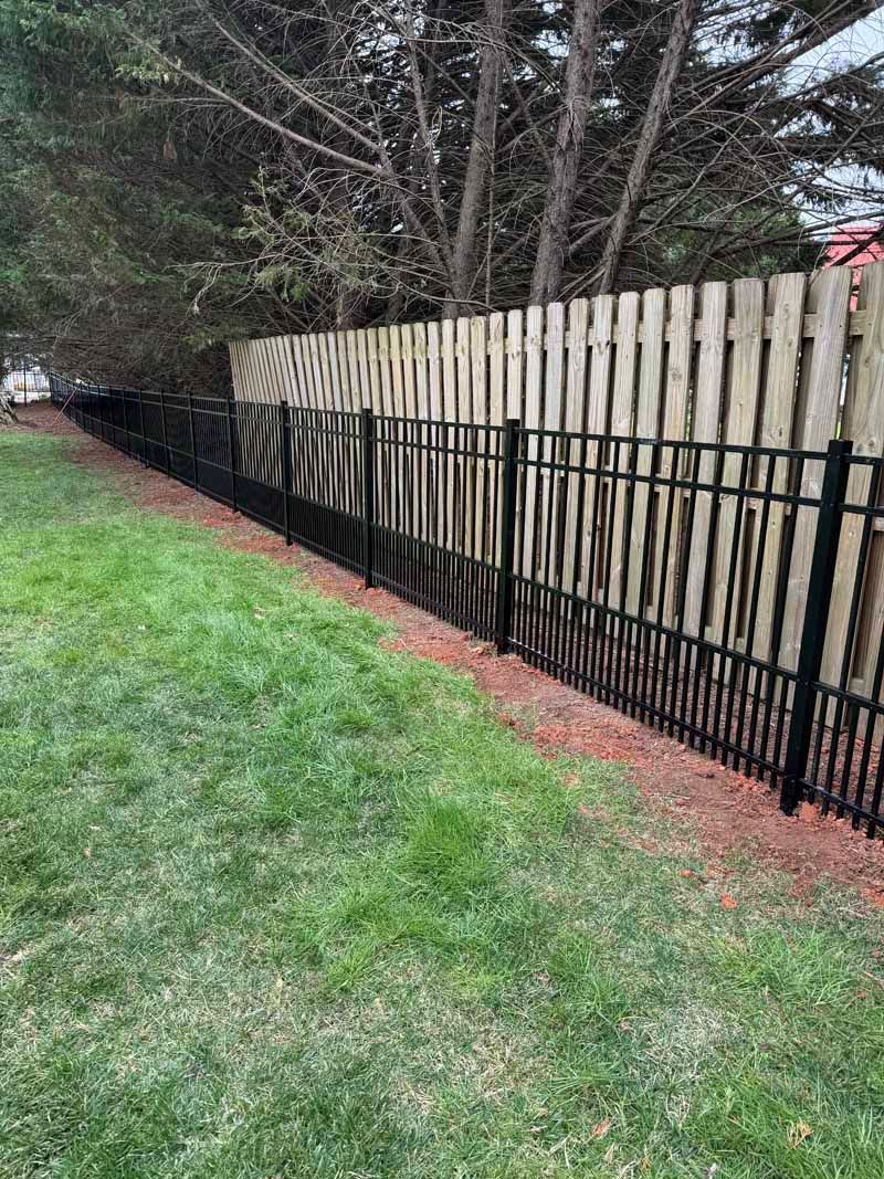 Wooden privacy fence beside a grassy yard with a black wire barrier along the bottom