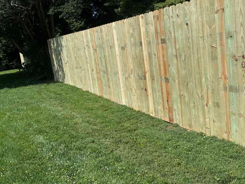 Long wooden fence beside a grassy yard on a sunny day