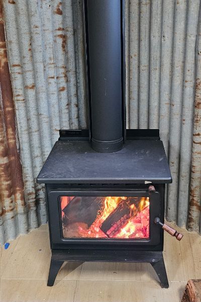 A wood stove is sitting in front of a tin roof.