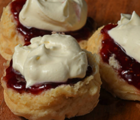 Three scones with jam and whipped cream.