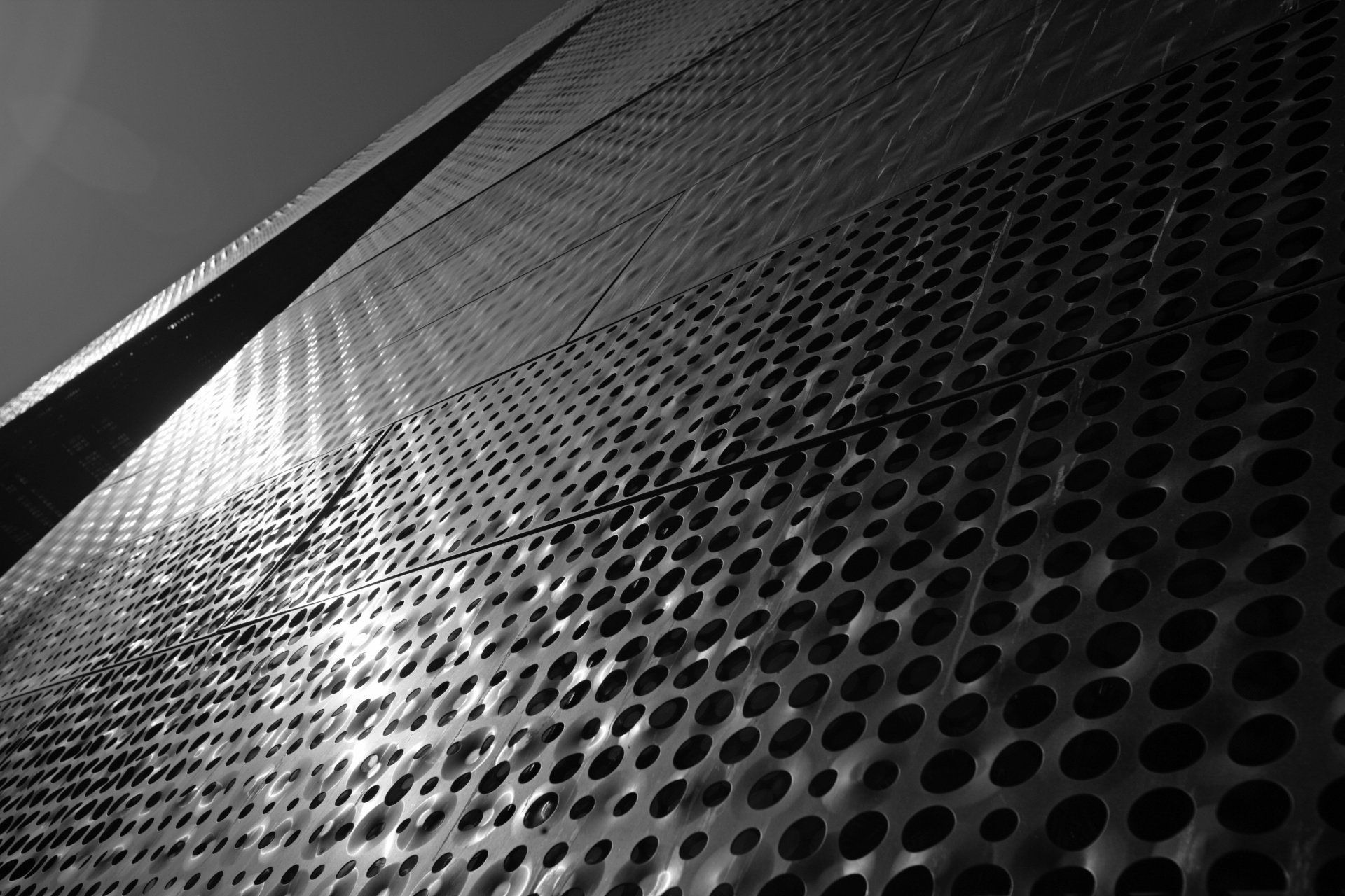A black and white photo of a metal wall with holes in it